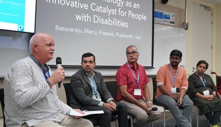 A diverse group of people on stage with a background reading, "Technology as an innovative catalyst for people with disabilities.